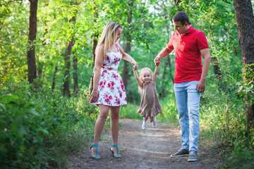 Fototapeta premium Mom and dad hold their daughter hands. Happy successful family.
