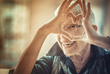 Senior woman making a heart shape, cute and lovely
