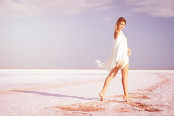 Girl walking on the salt lake, with abstract lines of sand. The concept of tourism, recreation, Spa treatments.
