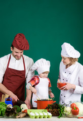 Child with parents cooking at kitchen table. Adorable kid in chef hat. Happy loving family preparing dinner together. Homemade food. Isolated. Preparation to dinner. Kitchen tools. Isolated.