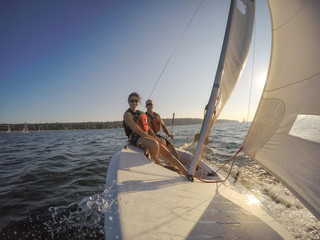 Naklejka premium Couple friends sailing on a small boat in the ocean during a vibrant sunset. Taken near Jericho, Vancouver, BC, Canada.
