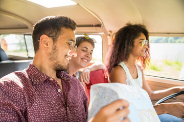Mixed group of happy young people going on holiday in a van
