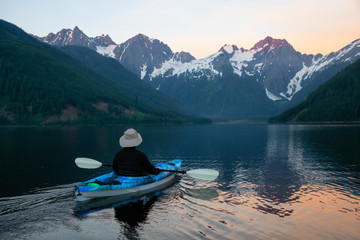 Fototapeta na wymiar Adventurous man kayaking in the water surrounded by the Beautiful Canadian Mountain Landscape. Taken in Jones Lake, near Hope, East of Vancouver, BC, Canada.