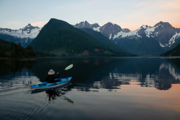 Adventurous man kayaking in the water surrounded by the Beautiful Canadian Mountain Landscape. Taken in Jones Lake, near Hope, East of Vancouver, BC, Canada.