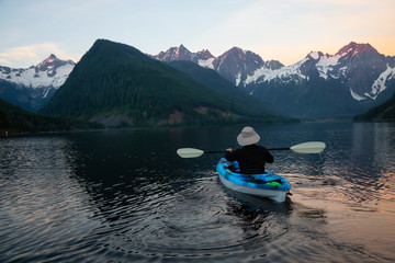 Fototapeta na wymiar Adventurous man kayaking in the water surrounded by the Beautiful Canadian Mountain Landscape. Taken in Jones Lake, near Hope, East of Vancouver, BC, Canada.