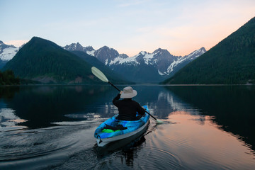 Adventurous man kayaking in the water surrounded by the Beautiful Canadian Mountain Landscape. Taken in Jones Lake, near Hope, East of Vancouver, BC, Canada.