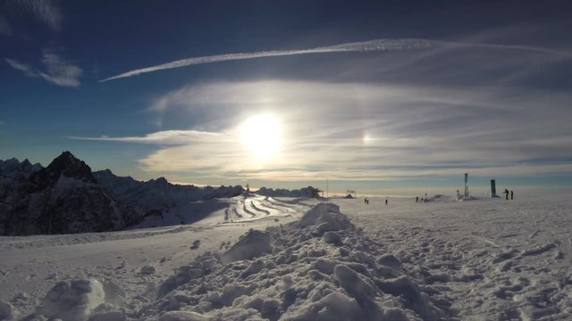 People skiing in the distance at the summit of a glacier, on a bluebird day, in the glorious French Alps.
