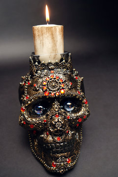 Skull decorated with colorful stones on black background
