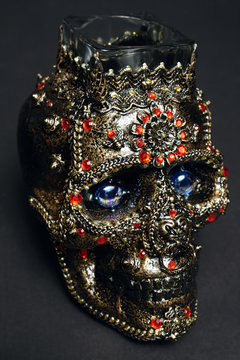 Skull decorated with colorful stones on black background