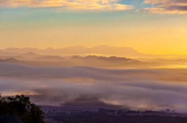Fototapeta premium Mountain ridges protruding above low clouds at vivid sunset in Australia