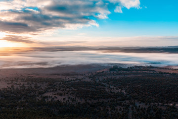 Low clouds over land, mountains, and trees at sunrise