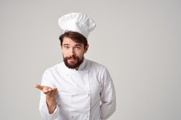 a cook with a beard in his uniform holds a free place on his hand