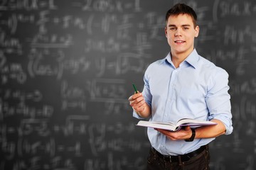 Young teacher near chalkboard in school classroom