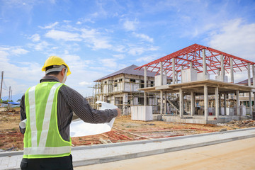 Professional engineer architect worker with protective helmet and blueprints paper at house building construction site