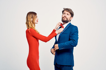 a woman in a red dress straightens a butterfly for a man