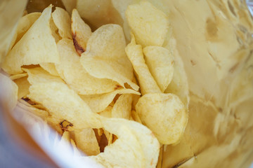 Potato chips in open snack bag close up