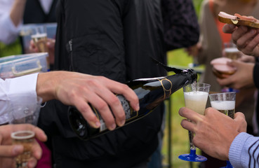 the hand of the man in the white shirt pours champagne on a holiday in the open air