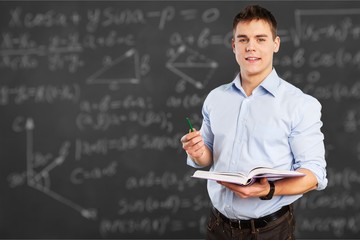 Young teacher near chalkboard in school classroom