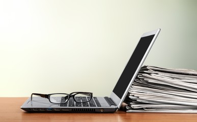 Laptop and black glasses on background