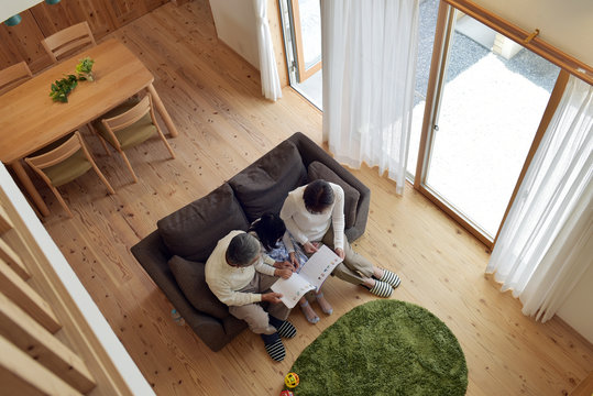 リビングで孫と絵本を読む祖父母・俯瞰