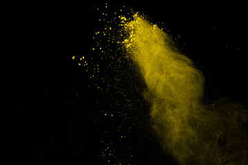 Abstract of yellow powder explosion on black background. Yellow powder splatted isolate. Colored...