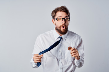 surprised business man holding a tie with bitcoin and a calculator on a light background