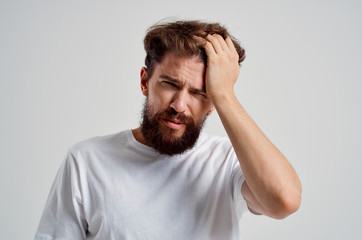 man with a beard holding his head in pain
