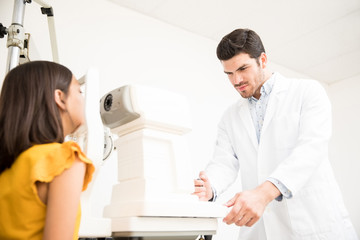 Optician with tonometer and patient at eye clinic