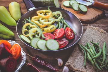 cut peppers, tomatoes and bean pods in a frying pan