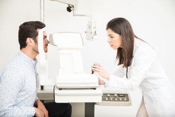 Young ophthalmologist examining patient in clinic