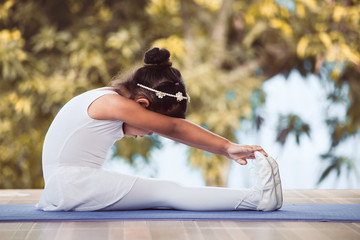 Cute asian child girl doing stretching exercises and practicing a ballet