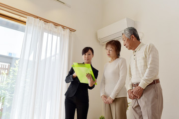 Obraz premium 住宅を内見するシニア夫婦と不動産会社のビジネスウーマン