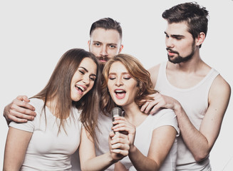 Portrait of happy girls and guys singing in microphone over white background.