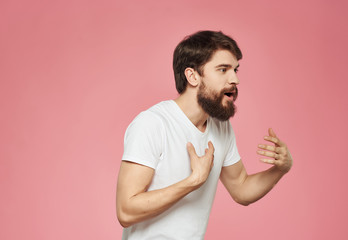 a man with a beard in a white T-shirt pink background