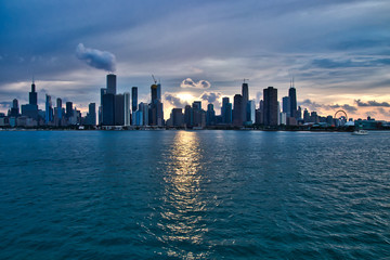 Fototapeta premium Sunset over the city of Chicago skyline with added interest in cloudscape and reflections during summer.