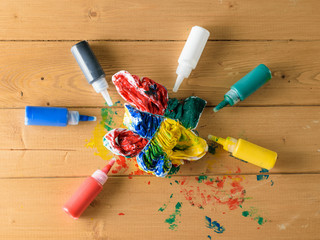 Tubes of fabric paint and a painted t-shirt on a wooden rustic table.