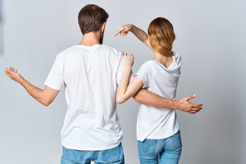 young couple in white t-shirts stand with their backs to the camera logo