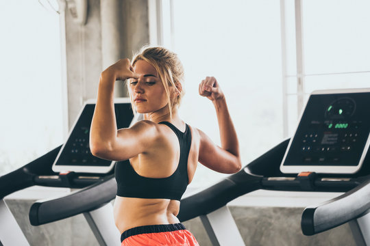 Portrait of Attractive young woman in sportswear showing her muscles at the gym