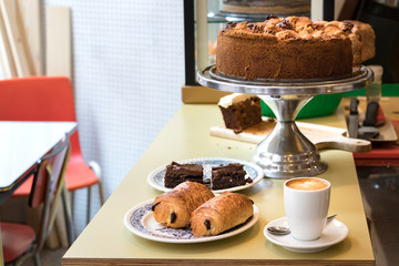 A cup of coffee espresso with pains au chocolat, bownies and a dutch apple pie.