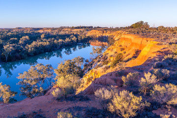 Fototapeta na wymiar Scenic and calm Murray River under sandstone cliffs at beautiful glowing sunset