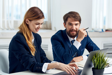 business man holding a pen in his hand and a woman typing on a keyboard