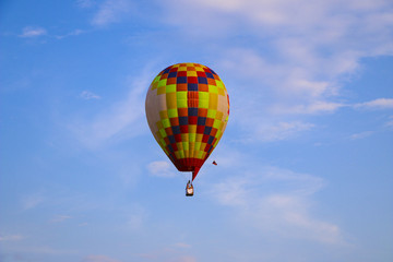colorful hot air balloon against blue sky. hot air balloon is flying in white clouds. beautiful flying on hot air balloon