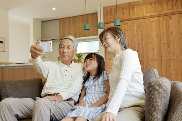 リビングで自撮りをする老夫婦と孫