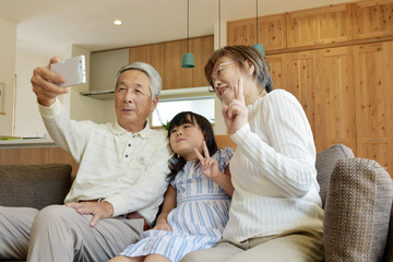 リビングで自撮りをする老夫婦と孫