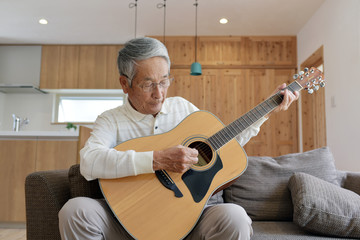 リビングのソファでギターを弾くシニア男性