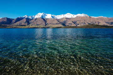 Looking across to snow dusted mountains adjacent to Lake Wakutipu on a clear blue sky day. New...