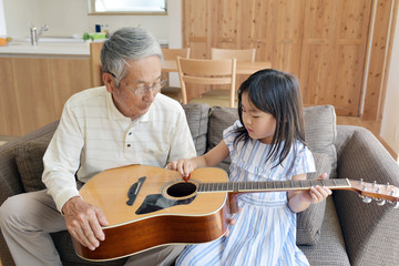 ギターを弾くおじいちゃんと孫娘