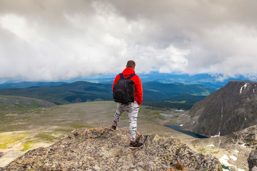 Fototapeta premium Man hiker enjoy the view at sunset mountain peak cliff.Photographer traveler on high mountaint Stylish man hiking. Travel Lifestyle and survival concept rear view.