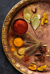 Spices and seasonings in measuring spoons and on an old copper tray