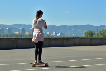 August 1, 2018. Krasnoyarsk. Russia. A young teenage girl is rolling on a seattle card and communicating on a smartphone.